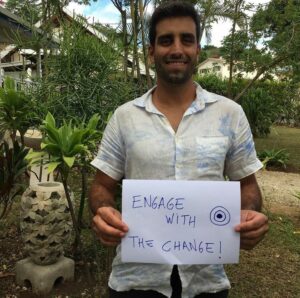 EWB field professional Daniel in Vanuatu holding a sign that says 'Engage with change'