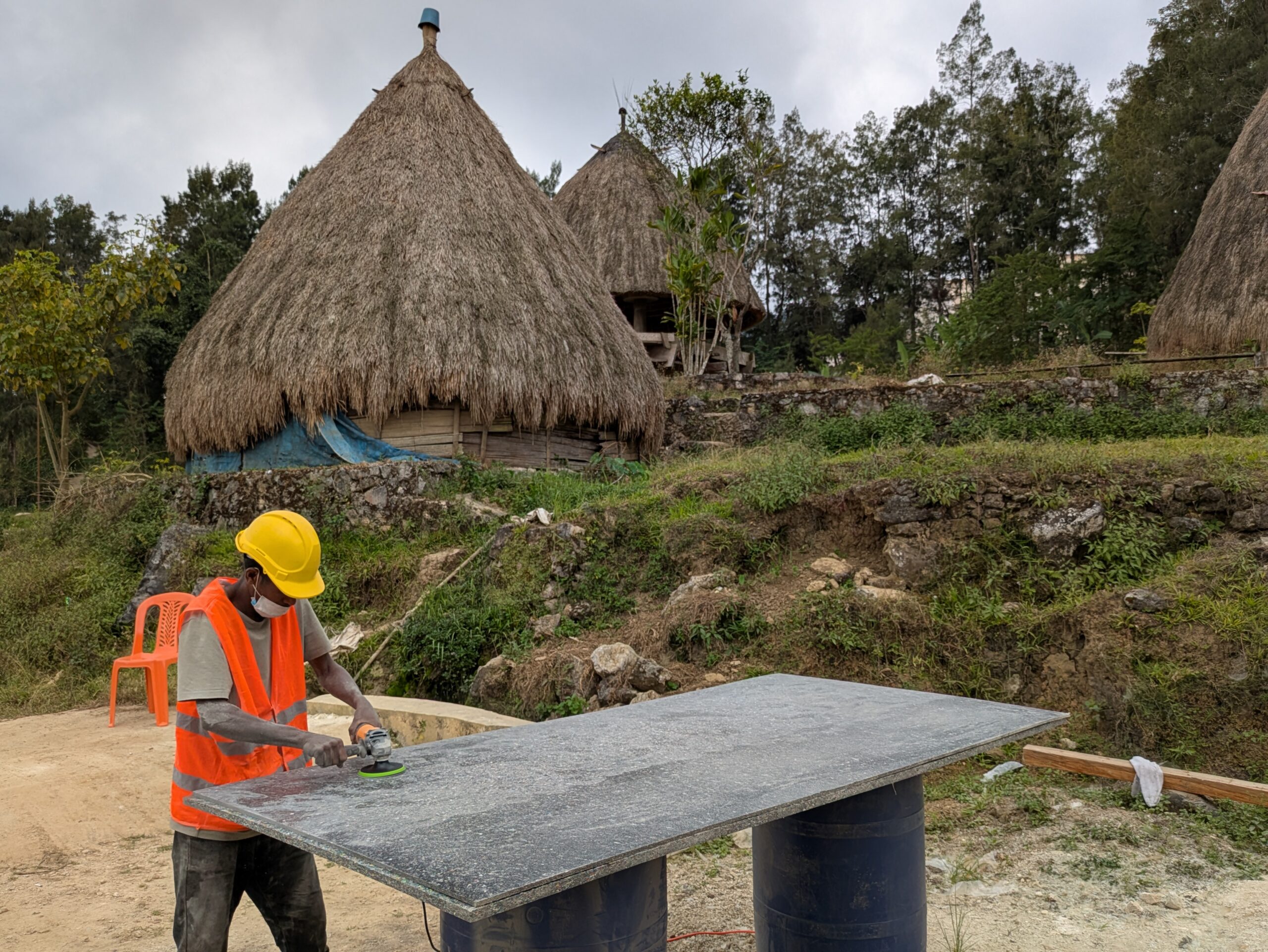 A man using power tools with a hut behind him